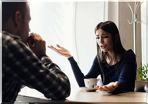 An upset woman is sitting in a cafe talking to her boyfriend.