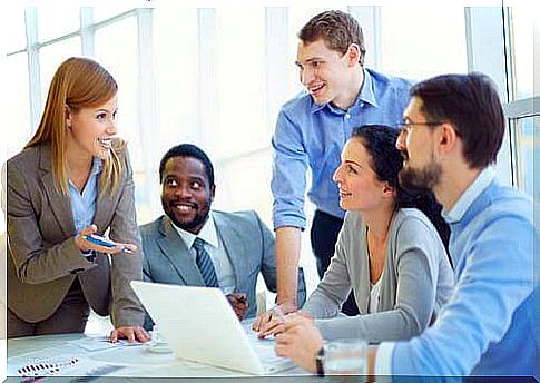 A group of employees are sitting in front of a laptop in a meeting.