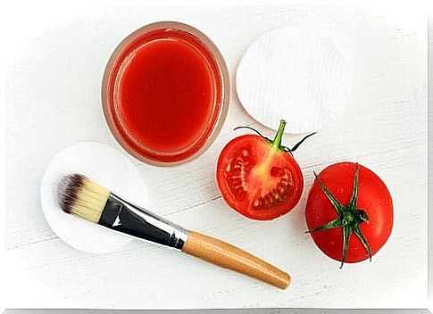 A bowl of tomato juice, two tomatoes, a brush and cotton balls are shown.