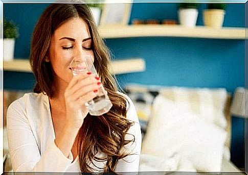 A woman has her eyes closed and is drinking a glass of water.